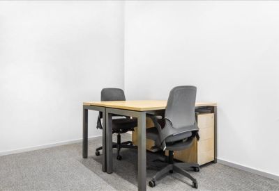 Internal two-person office suite with minimalist desks and grey chairs.