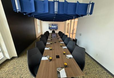 Long boardroom table under a unique blue geometric acoustic ceiling installation.