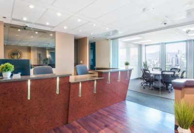 Modern reception area with wood-paneled desks and a view into a glass-walled meeting room.