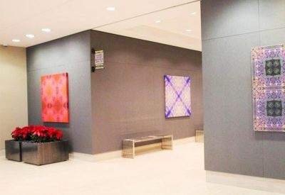 Bright lobby area featuring grey feature walls, colorful abstract art, and red poinsettia plants.