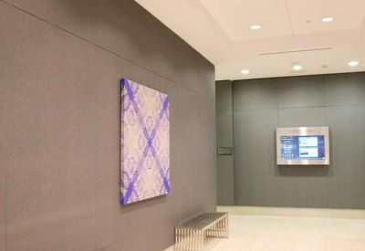 Building hallway with a purple patterned art piece and a minimalist metal bench.