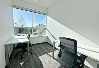 Bright private office suite featuring two desks, ergonomic chairs, and large windows with natural light.