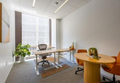 Private office with a light wood desk, ergonomic chair, and floor-to-ceiling window.