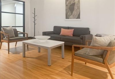Comfortable lounge area with wood flooring, grey sofa, and wooden armchairs.