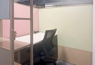 Private glass-walled office pod with a white desk and ergonomic task chair.