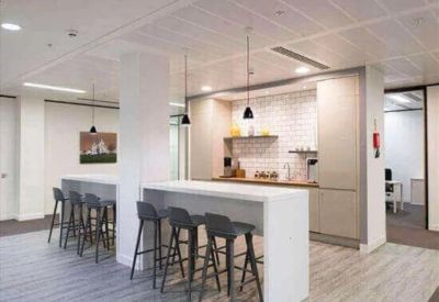 Bright communal kitchen and breakout area with high-top seating and modern pendant lighting.