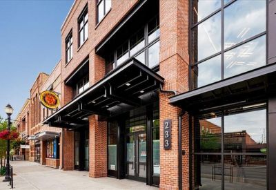 Entrance to the building featuring brick walls, black metal awnings, and large glass windows.