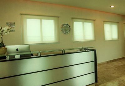 Minimalist reception area featuring a sleek silver front desk and soft overhead lighting.