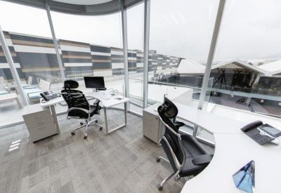 Private corner office with white desks and black ergonomic chairs overlooking the city.