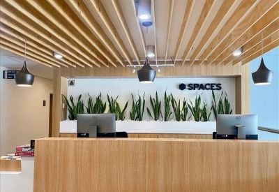 Reception desk with light wood panelling, modern pendant lights, and the company logo.