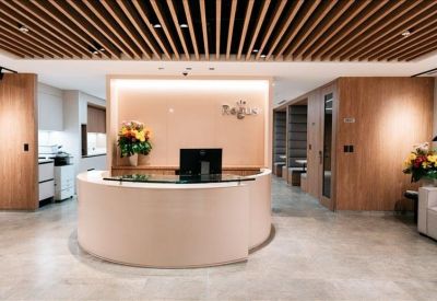 Reception area featuring a curved white desk and warm wood-slat ceiling.