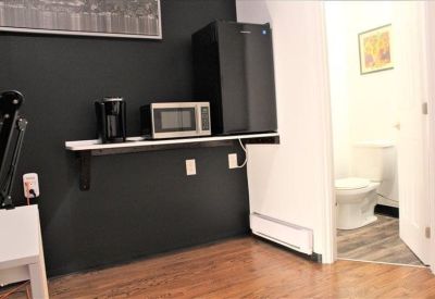 Communal kitchenette area with a microwave, coffee maker, mini-fridge, and view into a clean restroom.