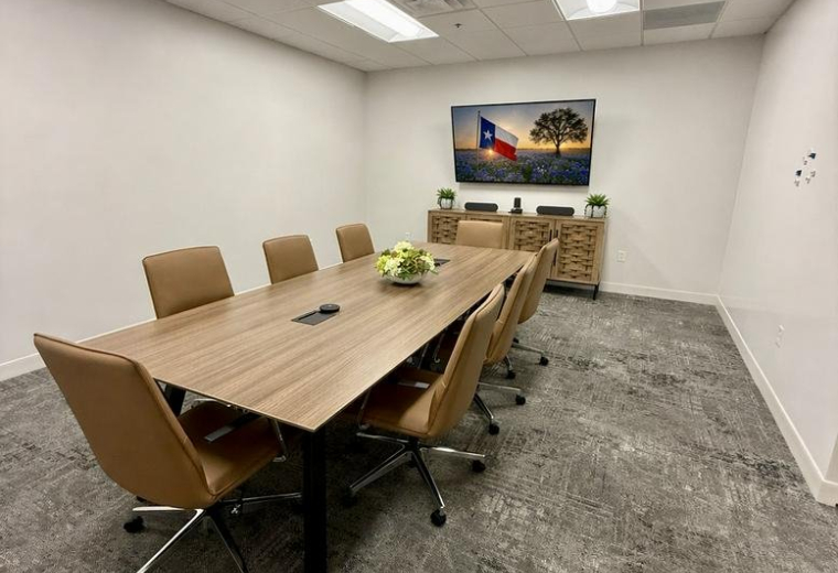Modern conference room at 122 West John Carpenter Freeway with a wooden table and leather seating.