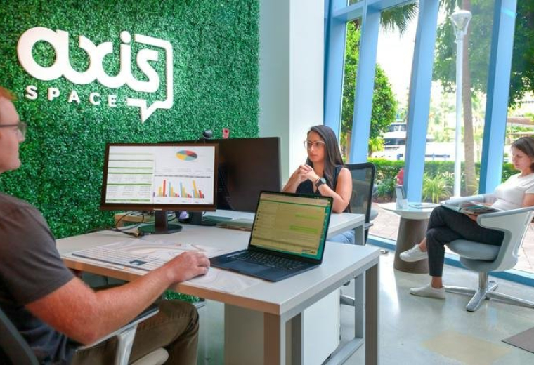 Wide view of a modern common area with a green moss wall and blue branding.