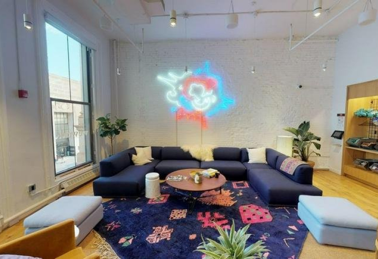Spacious communal lounge at 408 Broadway, New York City with a navy sectional sofa and colorful patterned rug.