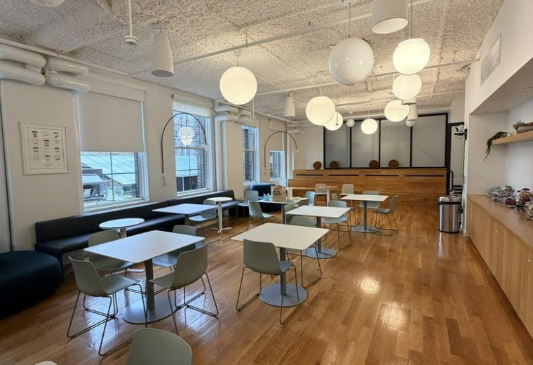 Spacious communal cafe area at 44 West 18th Street with wooden floors and globe lighting.