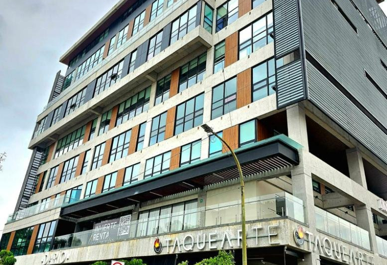 Exterior view of the contemporary multi-story glass and stone building at Av. Rubén Darío 425.