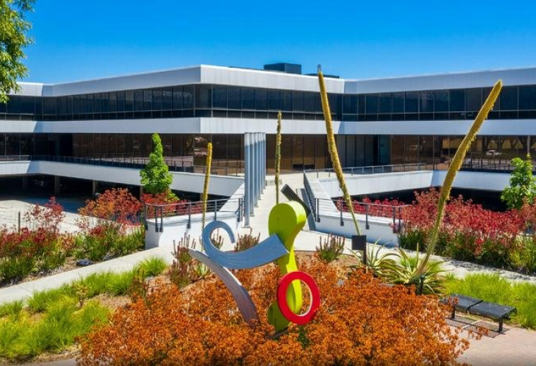 Exterior view of the modern office building at 10080 North Wolfe Road with vibrant landscaping.