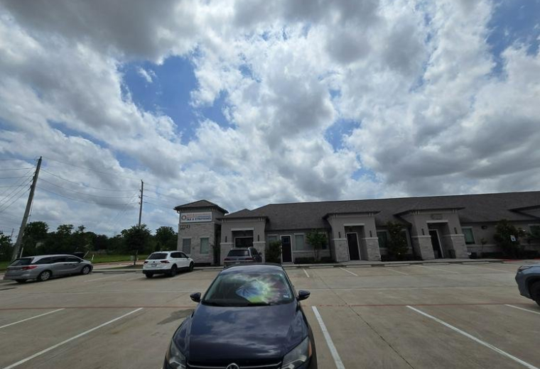 Wide view of the parking area in front of the single-story office building.