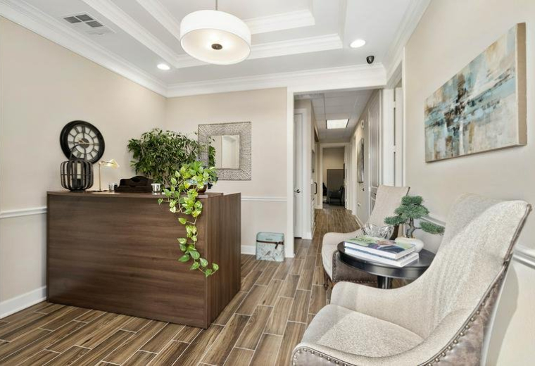 Reception area at 12440 Emily Court, Suite 102 featuring a wooden desk and plush seating.