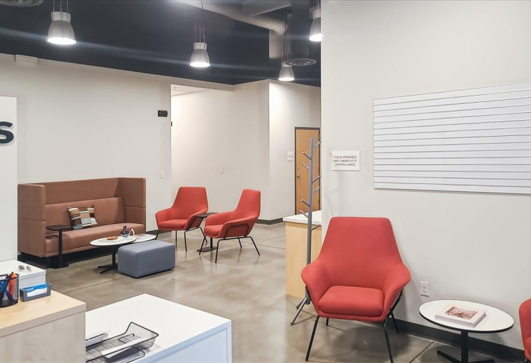 Bright communal lounge at 12709 East Mirabeau Parkway with vibrant red armchairs and a modern brown sofa.