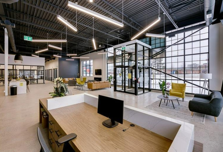 Spacious reception area at 407 Iroquois Shore Road with modern desks and a central glass elevator.
