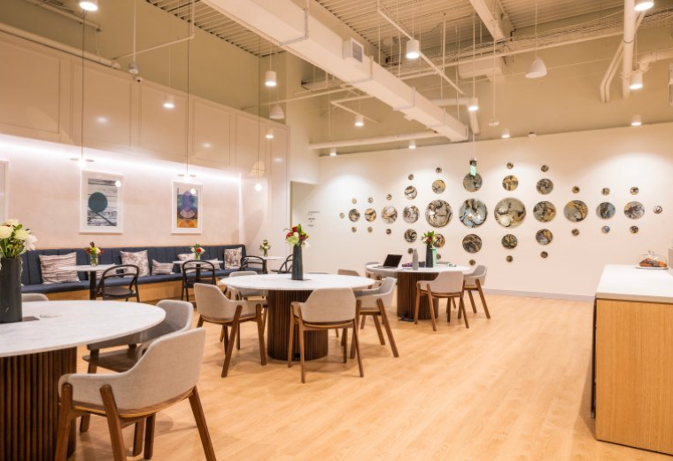 Spacious communal lounge at Legacy Place featuring round marble tables, velvet seating, and wall art.