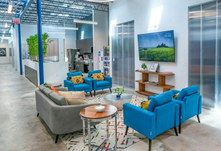 Spacious communal lounge at 8215 Long Point Road with blue armchairs and industrial ceilings.