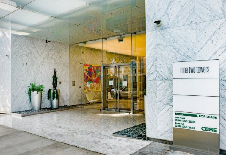 Exterior entrance of the Nine Two Towers building featuring marble walls and a modern glass canopy.