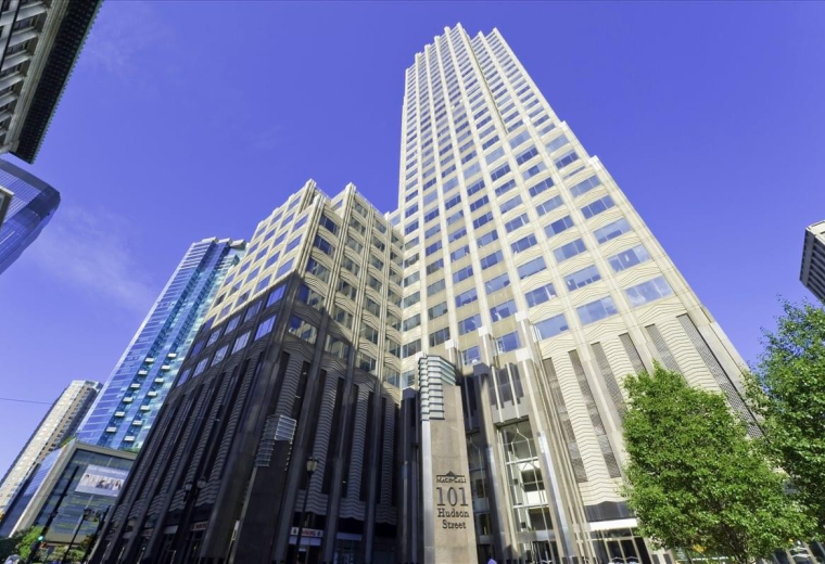 Exterior view of the towering 101 Hudson Street skyscraper against a clear blue sky.