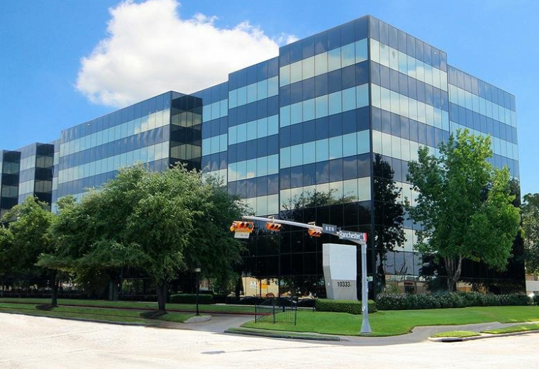Exterior view of the glass-facade 10333 Harwin Drive building with green landscaping.