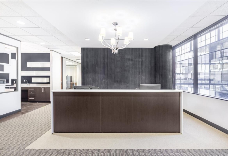 Reception area at 10777 Westheimer, Suite 1100 with a dark wood desk and designer chandelier.