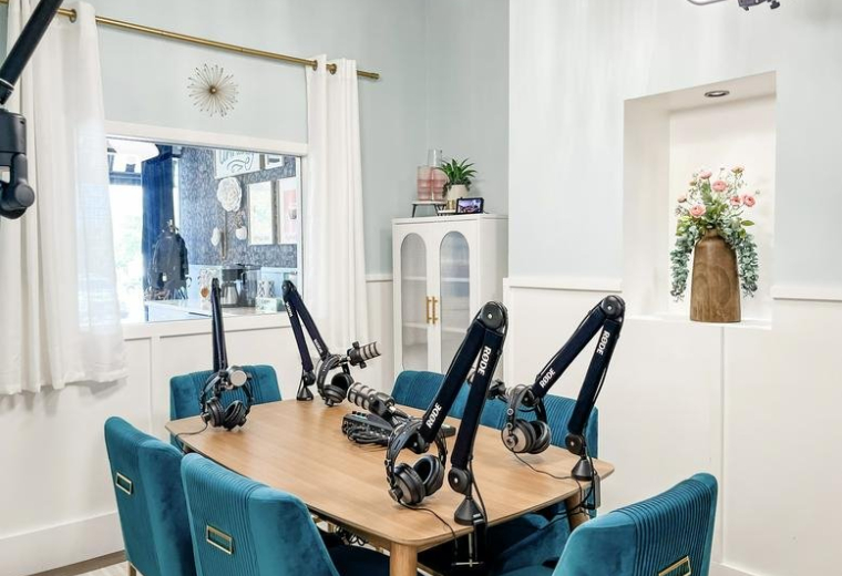 Podcast studio at 11854, Wurzbach Road with a wooden table, blue velvet chairs, and four professional microphones.