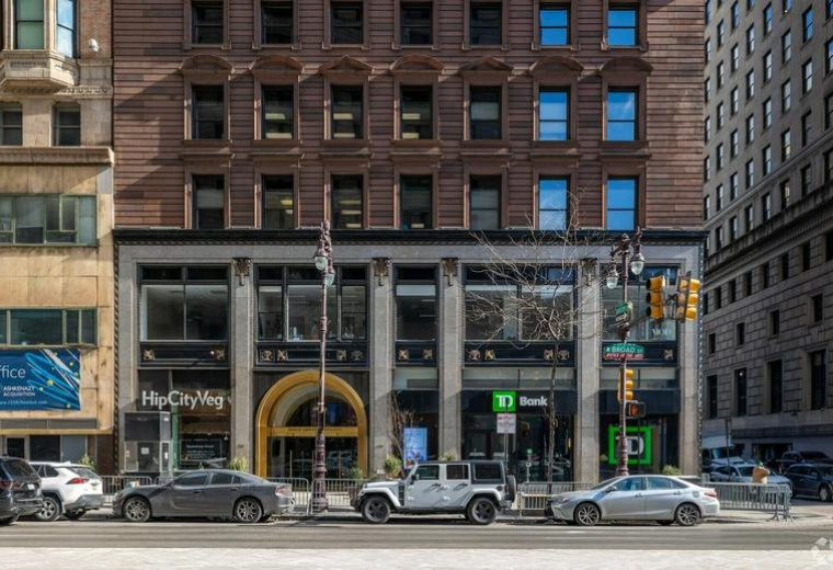 Exterior view of the historic brick facade with ground-level retail and a grand arched entrance.