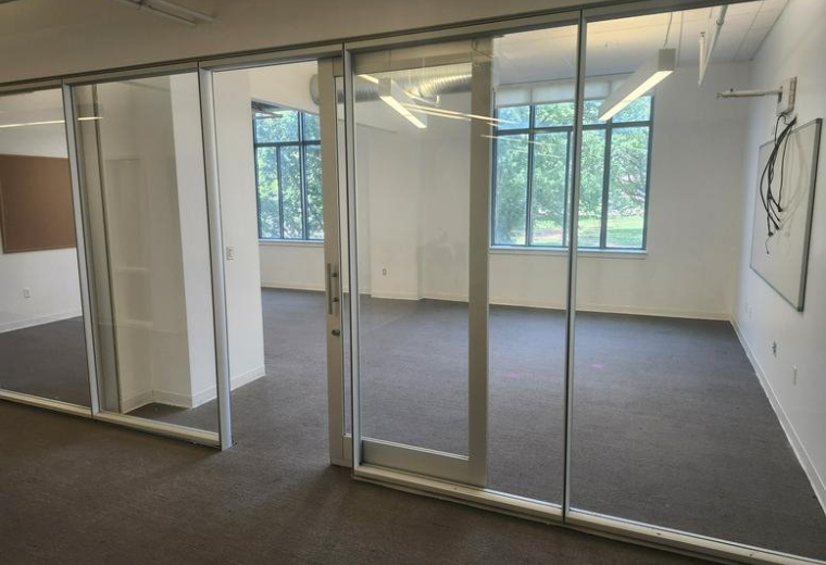 Private glass-walled office at 1226 Olive Street with natural light and view of greenery.