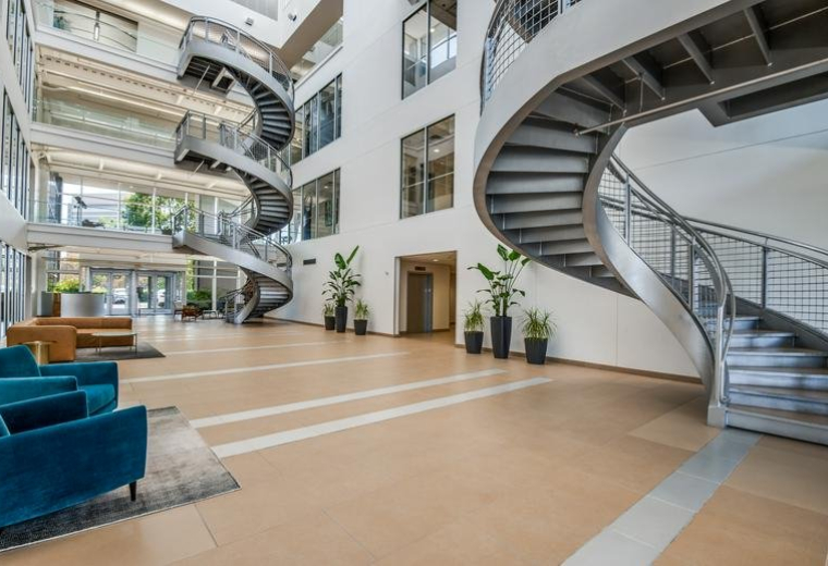 Spacious, modern lobby at 130, East John W Carpenter Freeway, Suite 220 featuring dramatic spiral staircases and plants.
