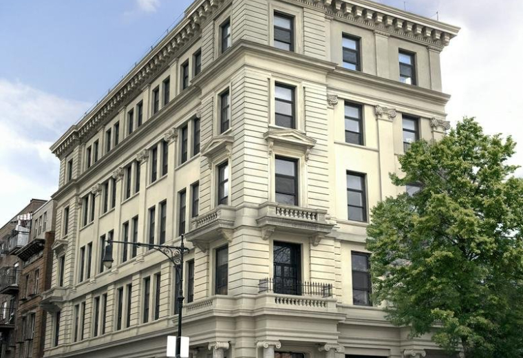 Five-story historic building with cream-colored stone details and large windows on a street corner.