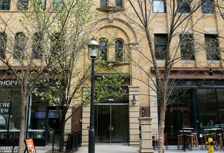 Exterior facade of the stone building at 140 Yonge Street with arched windows and tree-lined sidewalk.