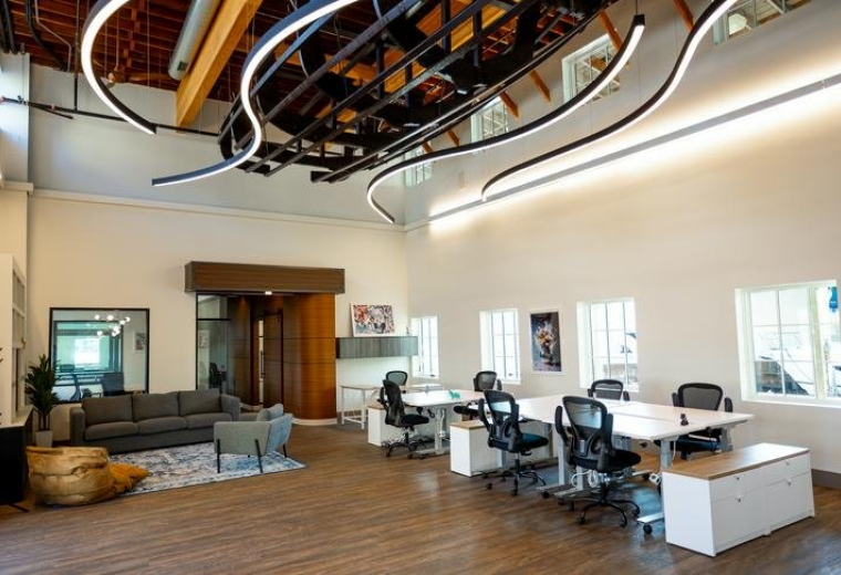 Spacious communal lounge and coworking area at Clipper Coworks with unique wave-shaped lighting and wood ceilings.