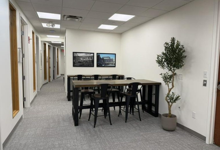 Spacious communal coworking area at 151, Merrimac Street with a large wooden table and hallway view.