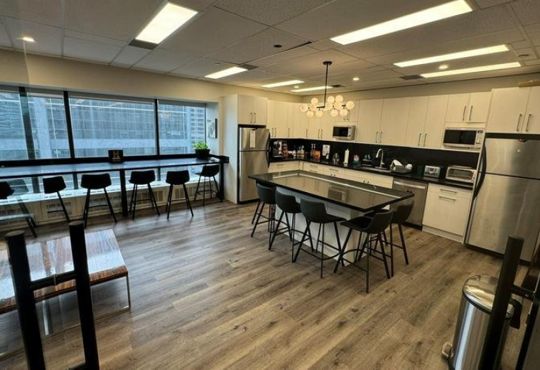 Modern kitchen and communal dining area with stainless steel appliances and breakfast bar.
