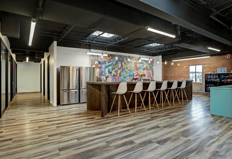 Spacious communal break area at 1923, Washington Avenue with wood floors and a colorful mural.