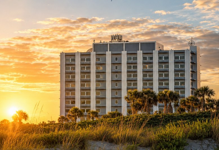 Low angle view of Cape Royal building behind beach dunes at sunset.