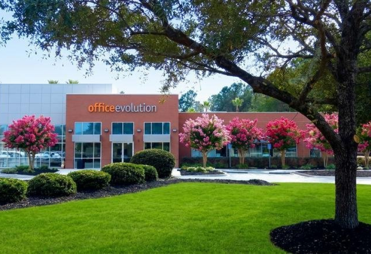 Exterior view of the Office Evolution building at 20 Martin Court with pink flowering trees and green lawn.