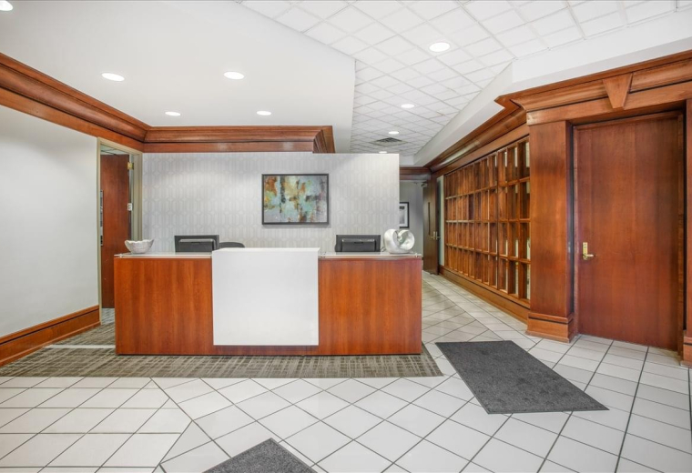 Reception area at 200 Prosperity Drive with a wood-fronted desk and expansive wood-paneled walls.