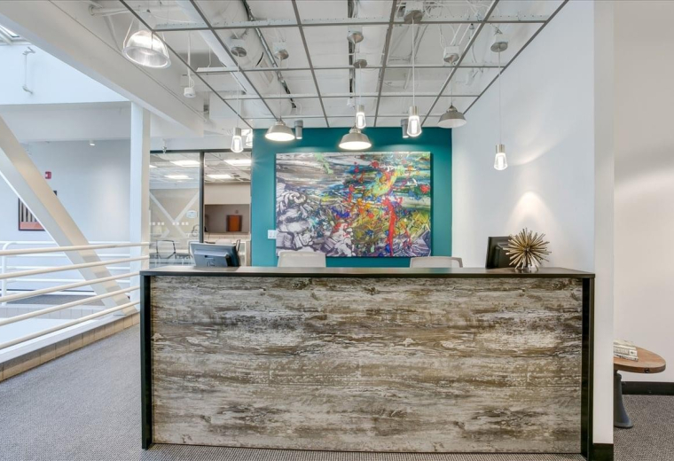 Reception area at 2001 Addison Street featuring a rustic wood desk and vibrant abstract art.