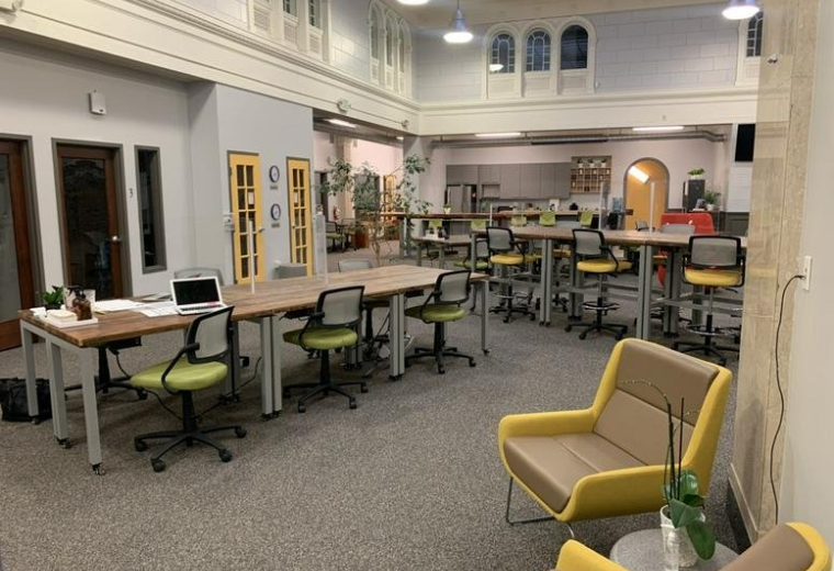 Spacious communal coworking area at 2081 Center Street, Berkeley, California with yellow accent chairs and wood tables.