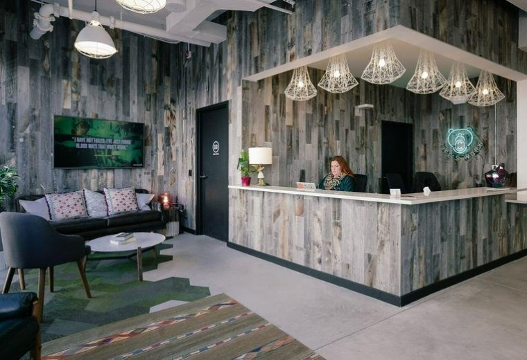 Reception area at 2120 University Ave with reclaimed wood walls and modern geometric pendant lights.