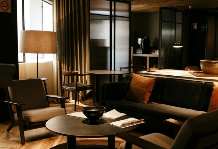 Cozy communal lounge with mid-century modern armchairs and wood ceilings.