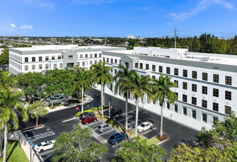 Exterior view of the white facade and palm trees at 2700 North Military Trail, Suite 150.